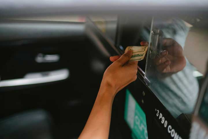 A passenger paying an Uber driver in cash