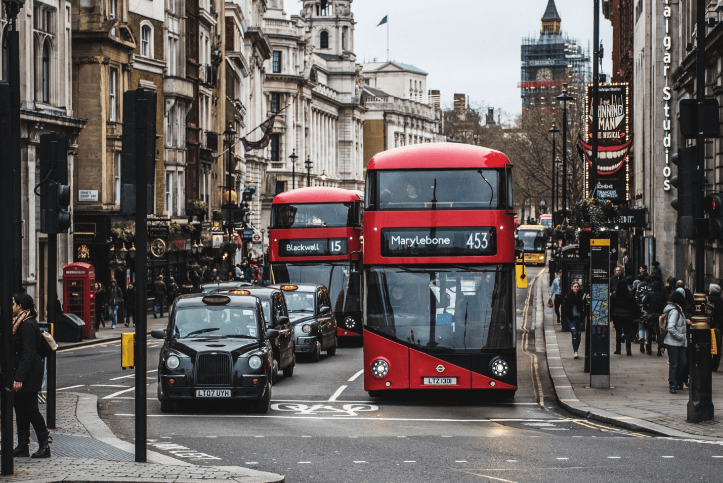 red buses and black taxis on a road in London