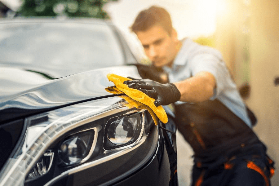 a photo of a man cleaning his car